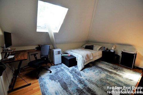 A bedroom with a bed, desk, and chair.