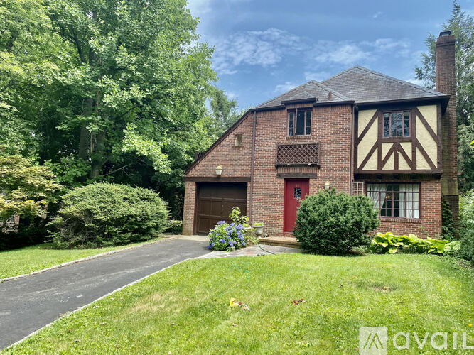 A house with a red door and a brick facade surrounded by greenery.