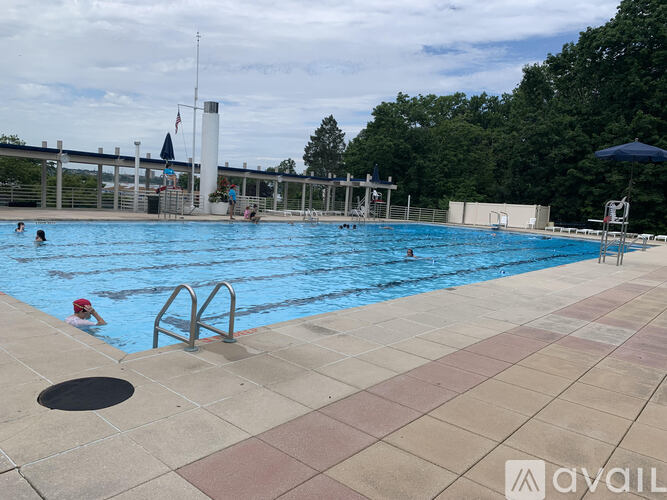 A large outdoor swimming pool with people swimming and relaxing.