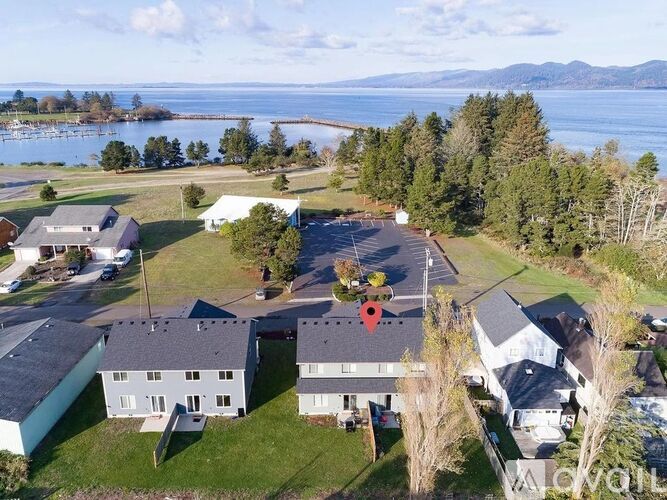 A bird's eye view of a residential area with a lake and mountains in the background.