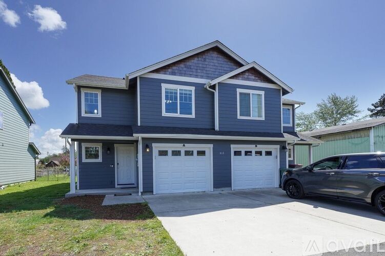 A two-story house with a garage and a car parked in front.