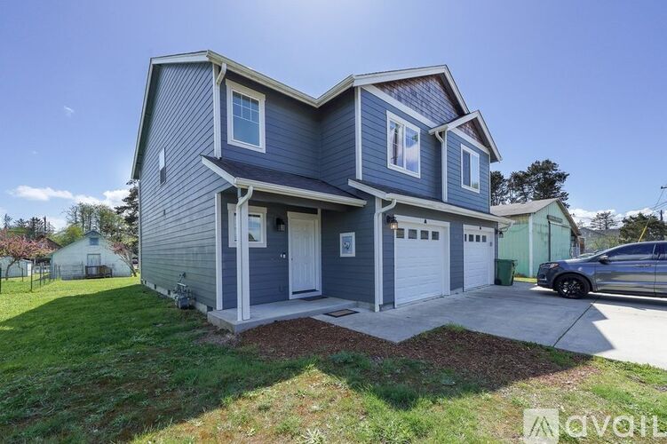 A two-story house with a garage and a car parked in front.