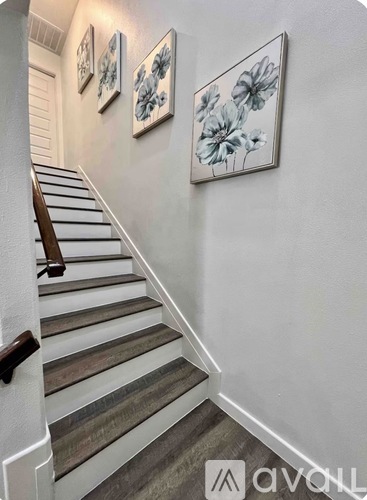 A staircase with a wooden handrail and a picture of a flower on the wall.