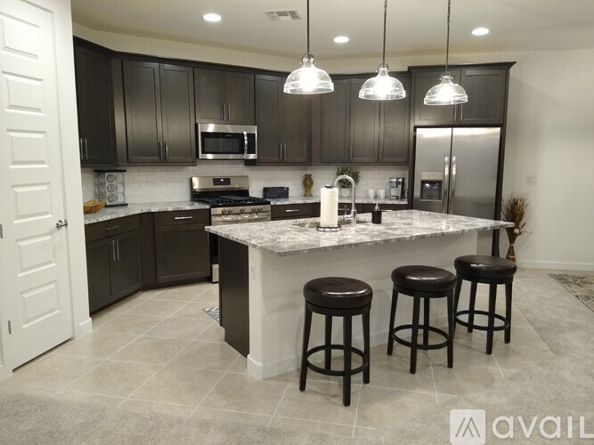 A kitchen with a marble countertop and black bar stools.