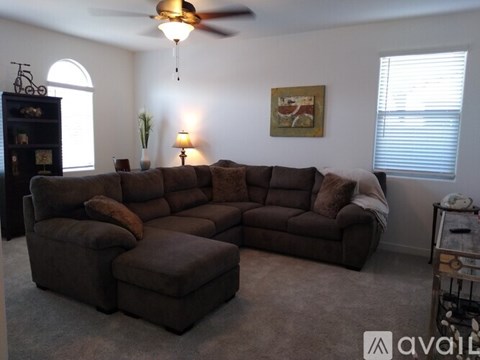 A living room with a brown sectional sofa and a small table with a lamp.