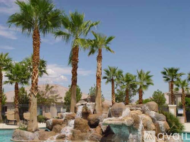 A pool surrounded by palm trees and rocks.