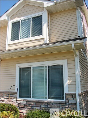 A house with a stone wall and a window with blinds.