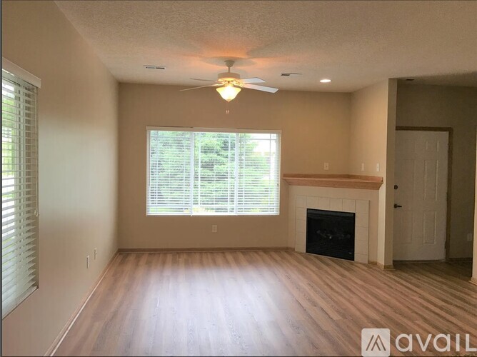 A living room with a fireplace and a window with blinds.