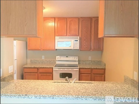 A kitchen with orange cabinets and a granite countertop.