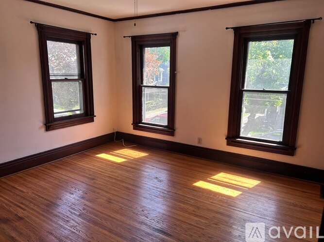 A room with wooden floors and three windows.
