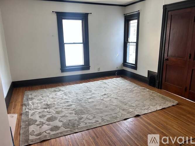 A room with a rug on the floor and a door on the right.