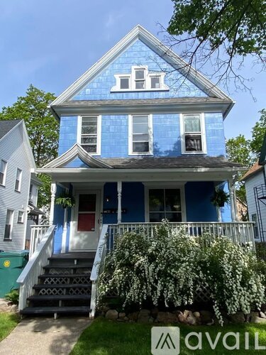 A blue house with white trim and a red door.