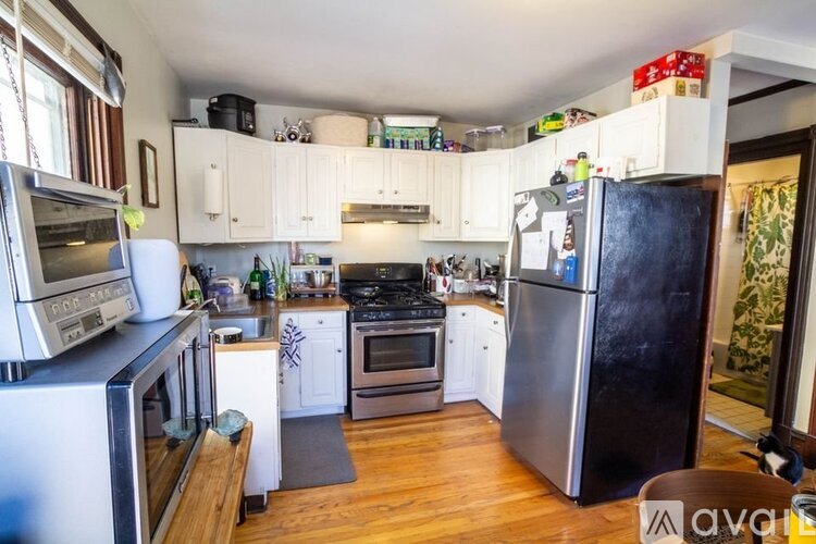 A kitchen with white cabinets and a black fridge.
