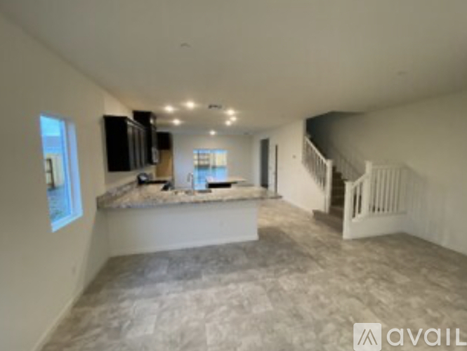 A spacious empty room with a counter and stairs.