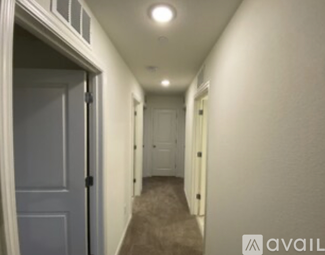 A hallway with a carpeted floor and white walls.