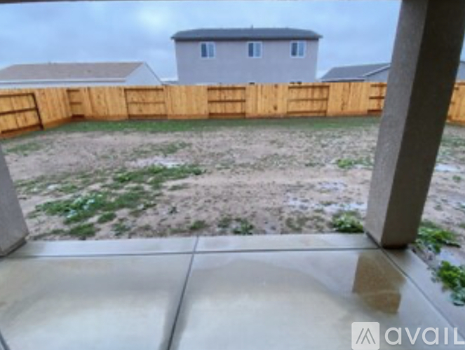 A backyard with a wooden fence and a house in the background.