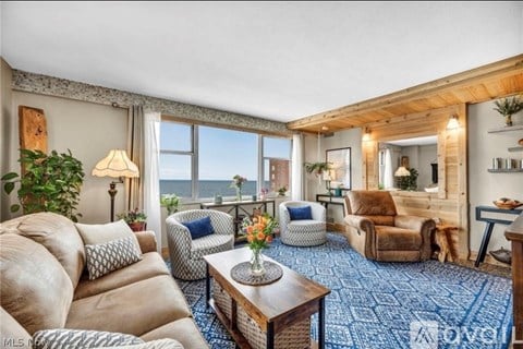 A living room with a large window overlooking the ocean.