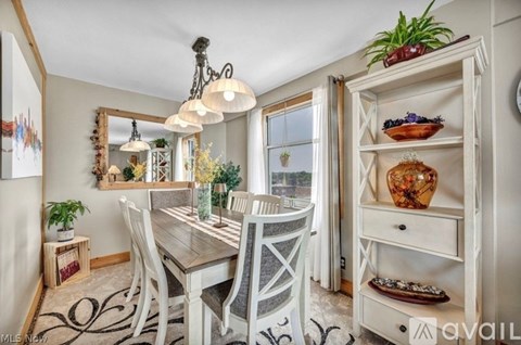 A dining room with a wooden table and chairs, a chandelier, and a cabinet with decorative items.