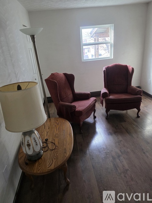 Two red chairs and a table with a lamp on it.