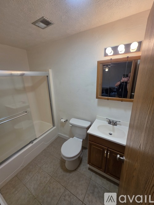 A bathroom with a toilet, sink, and mirror.