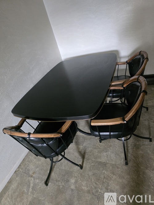 A black table with two chairs with leather seats and wooden armrests.