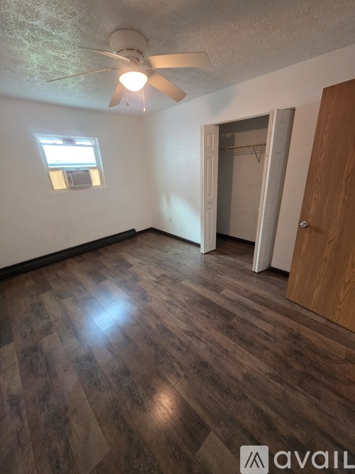 A room with a ceiling fan and wooden flooring.