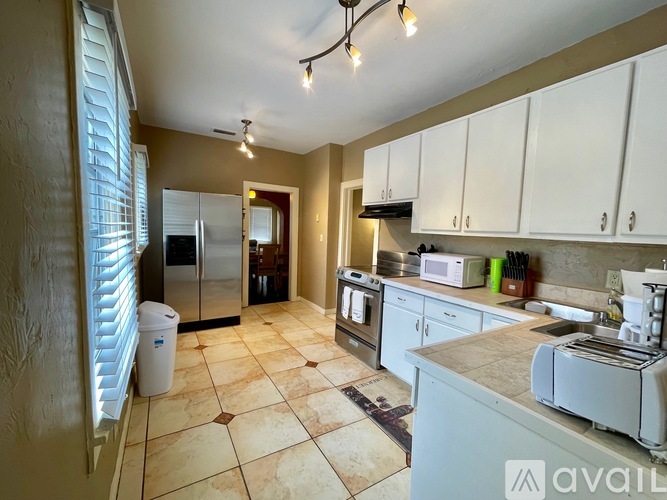 A kitchen with white cabinets and a tiled floor.