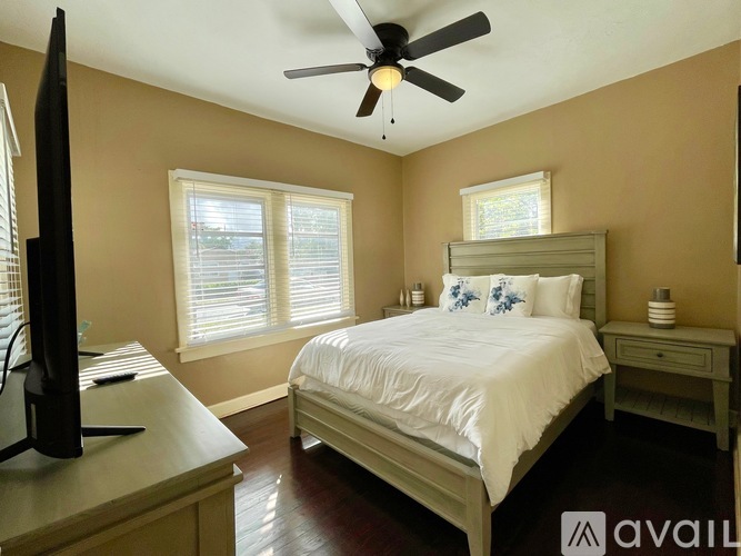 A bedroom with a bed, dresser, and television.