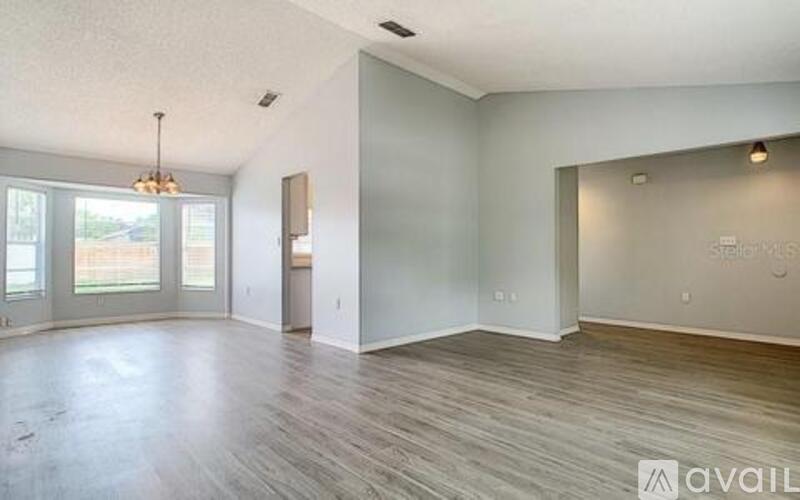 A spacious room with wooden flooring and a large window.