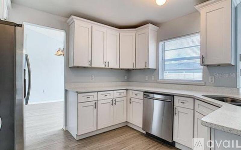 A kitchen with white cabinets and a black refrigerator.