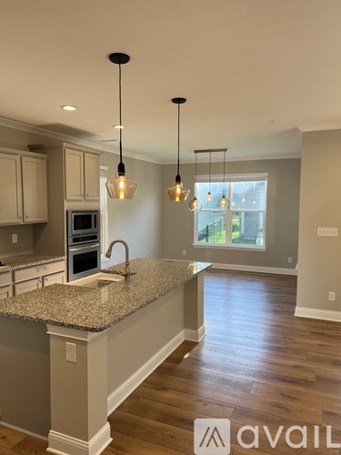A kitchen with granite countertops and pendant lights.