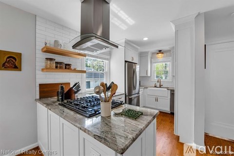 A kitchen with a marble countertop and white cabinets.