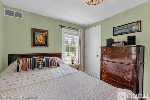 A bedroom with a bed, dresser, and two pictures on the wall.