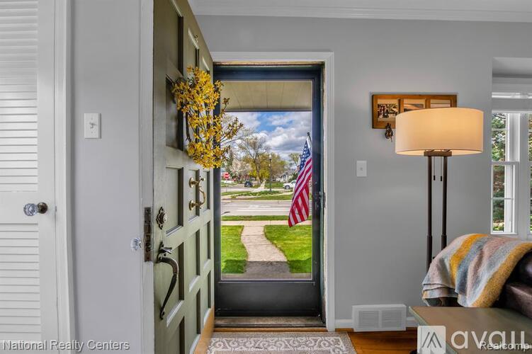 A view from the inside of a house looking out through a doorway to a lawn and trees.