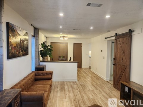 A living room with a brown couch and a wooden door.