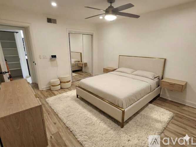 A bedroom with a large bed, a ceiling fan, and a wooden dresser.