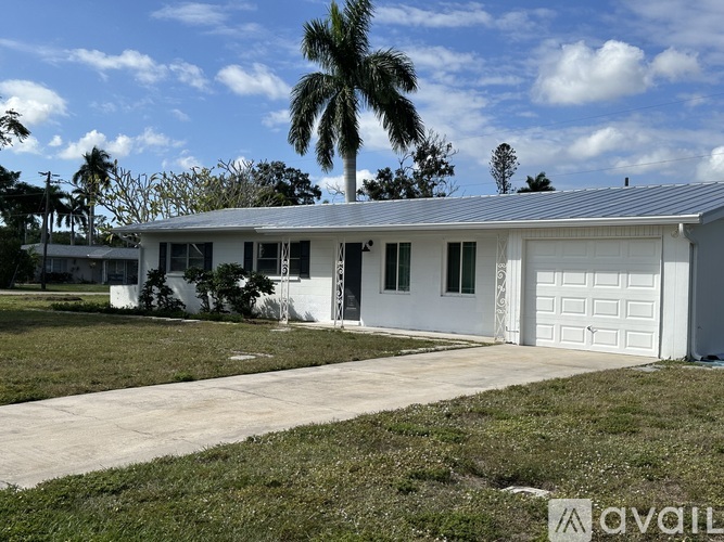 A white house with a garage door and a driveway in front.