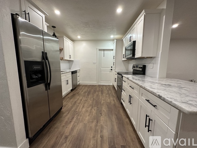 A kitchen with a refrigerator, microwave, and oven.