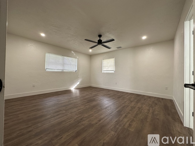 A spacious room with wooden flooring and a ceiling fan.