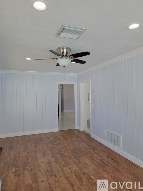 A room with a ceiling fan and wooden flooring.