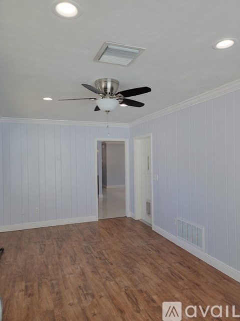 A room with a ceiling fan and wooden flooring.
