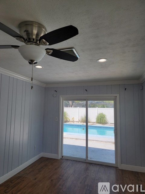 A room with a ceiling fan and a sliding glass door leading to a pool.
