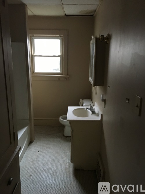 A bathroom with a toilet, sink, and window.