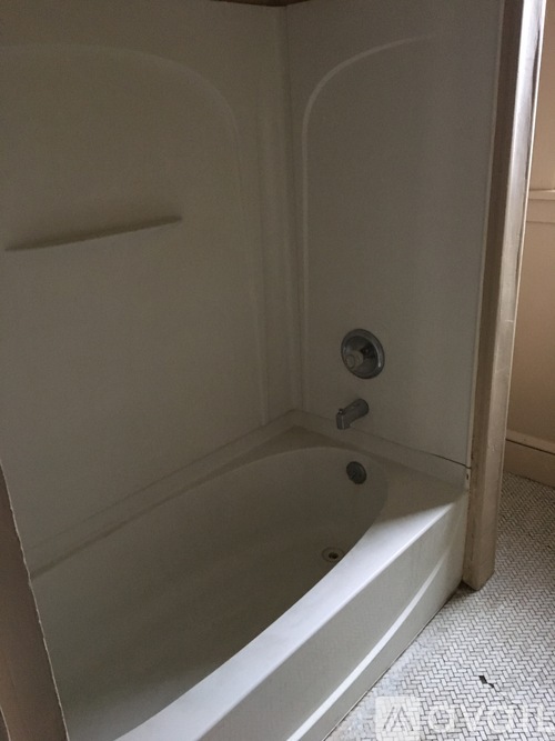 A white bathtub with a shower head and faucet.