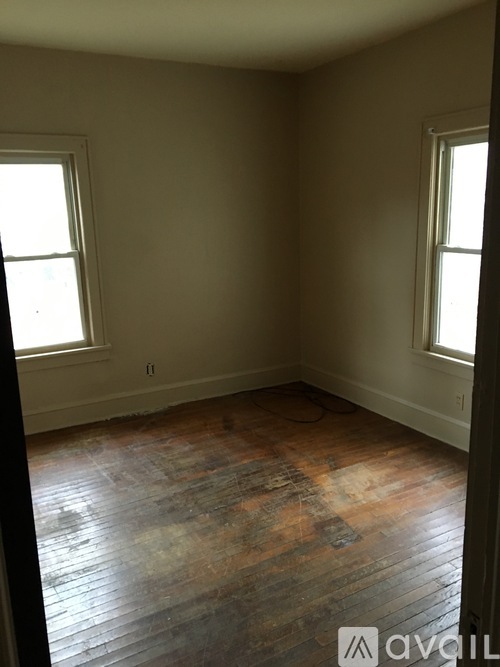 A room with wooden floors and two windows.