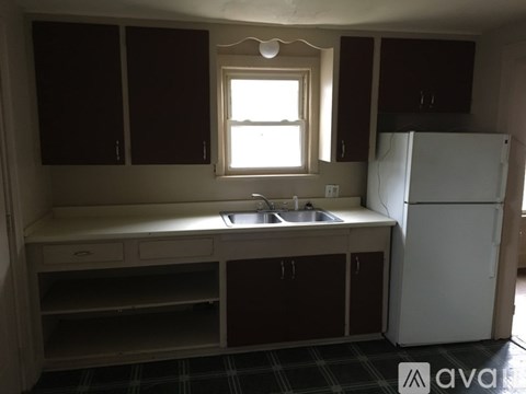 A kitchen with a white fridge, brown cabinets, and a window.