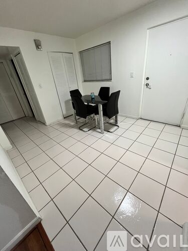 A white tiled room with a table and chairs.