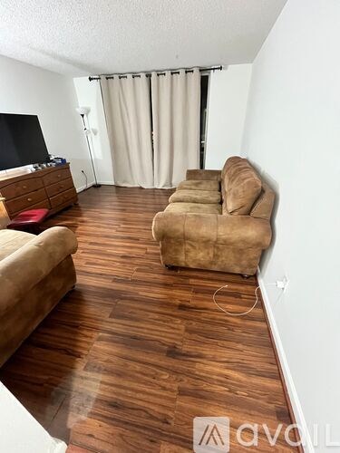 A living room with a brown sofa and a wooden floor.