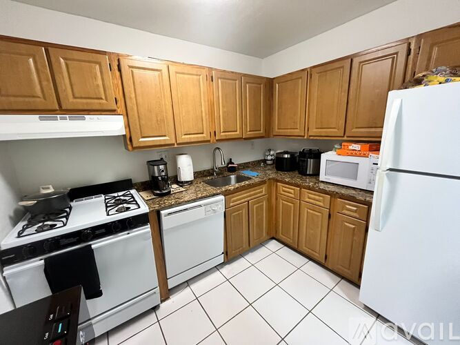 A kitchen with white appliances and wooden cabinets.