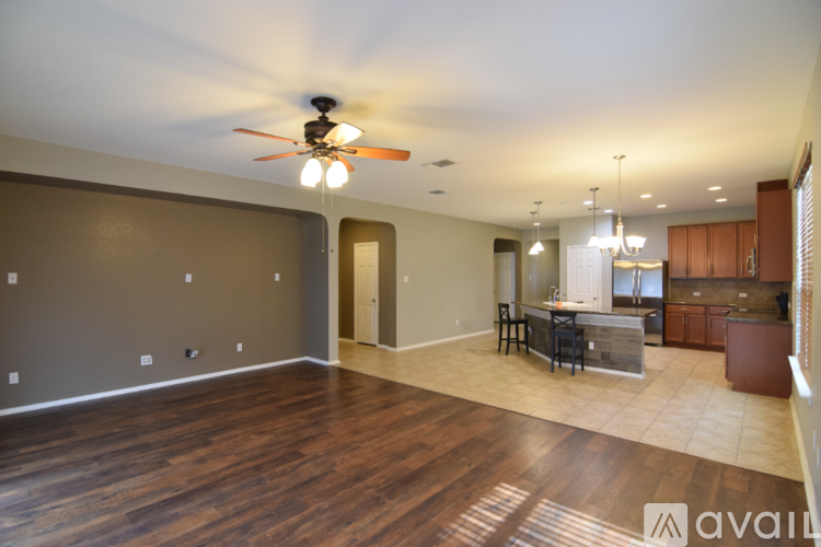 A spacious living room with a ceiling fan and hardwood floors.